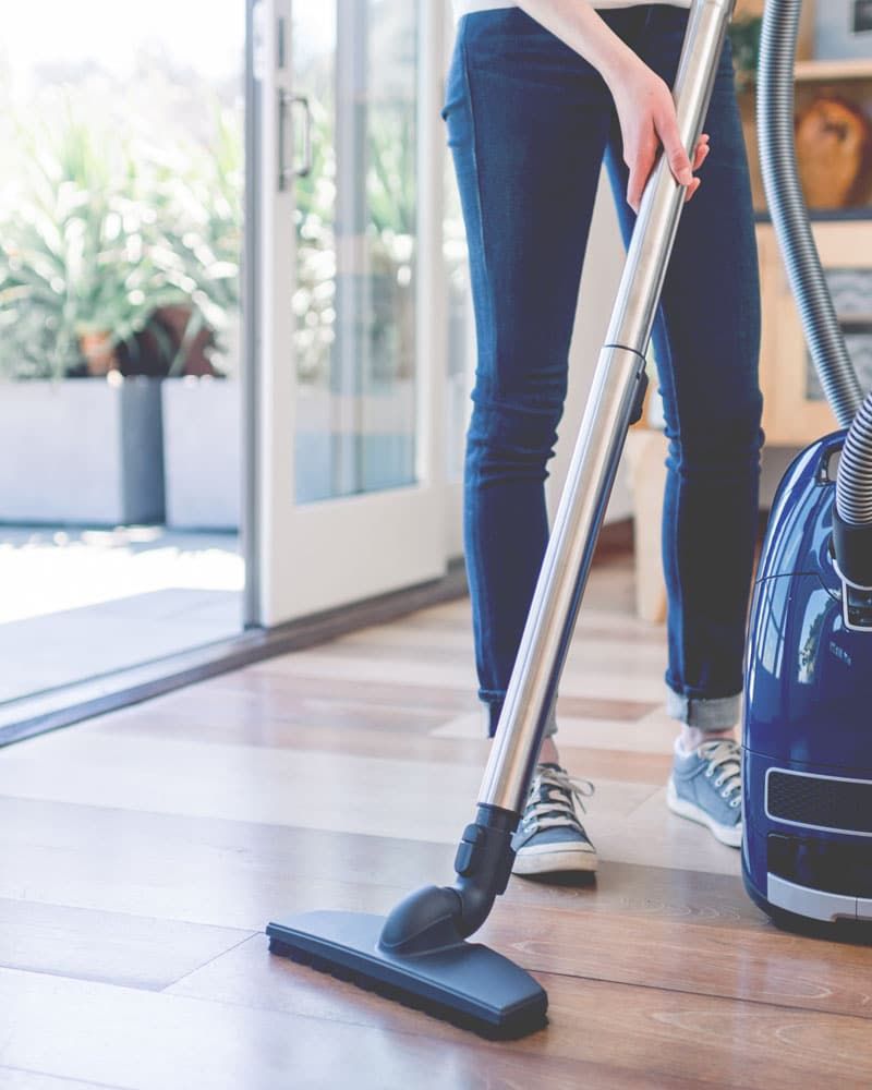 A cleaner vacuuming a bright wooden floor